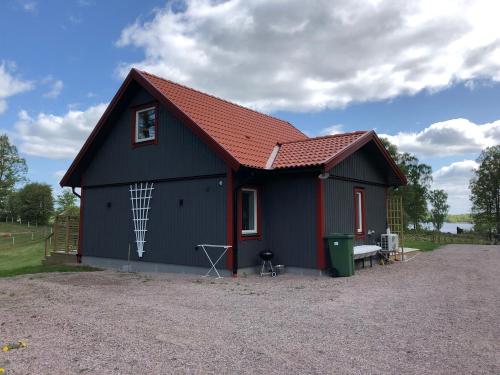 a black and red shed with a red roof at Joarsbo, Stuga 3, Klinten in Kalv