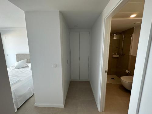 Ein weißes Zimmer mit einem Bett und einem Bad. in der Unterkunft LUXURY Apartaments Gran Canet in Canet d'en Berenguer