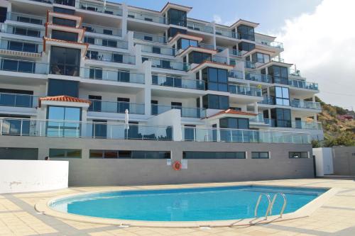 a large apartment building with a swimming pool in front of it at Cote D Atlantique by Homie in Caniço