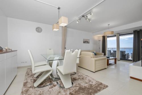 a dining room with a glass table and white chairs at Cote D Atlantique by Homie in Caniço
