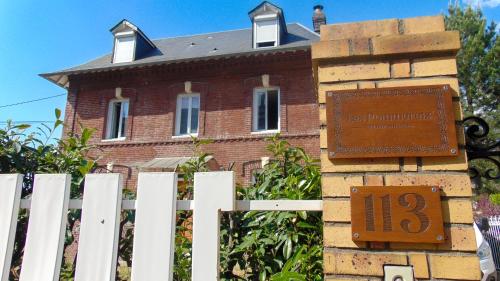 una cerca blanca frente a una casa de ladrillo en Les Pommerets, en Le Petit-Couronne