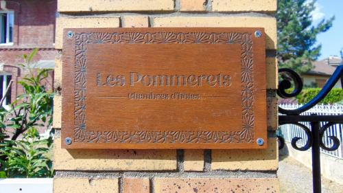 um sinal de madeira na lateral de um edifício de tijolos em Les Pommerets em Le Petit-Couronne