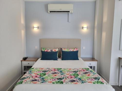 a bedroom with a large bed with blue pillows at Hotel Ancora Mar in Nazaré