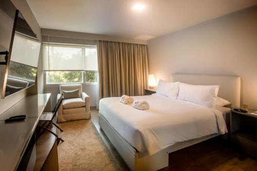 een hotelkamer met een bed, een stoel en een raam bij Luxurious 1BR Overlooking Lima Golf Club in Lima