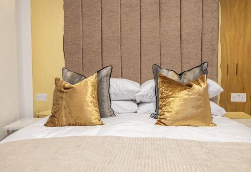 Una cama con cuatro almohadas encima. en The Pocklington - The Filbert Suite en Leicester