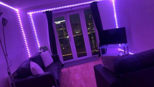 a living room with purple lights and a tv at 2 bedroom luxury apartment Birmingham city centre in Birmingham