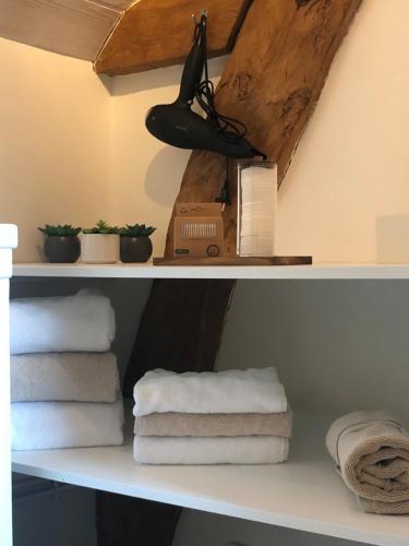 a shelf with towels and a box on it at La Parenthèse - Studio atypique - Piscine - Proche Le Mans in Amné-en-Champagne