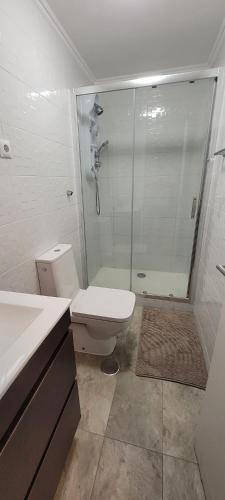 a white bathroom with a shower and a toilet at Village Cascais Guest House in Cascais
