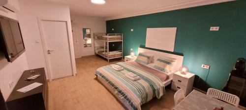 a bedroom with a green wall with a bed and a desk at Village Cascais Guest House in Cascais