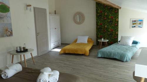 sala de estar con 2 camas y pared de flores en Maison de Vacances 8 à 15 pers à proximité du Canal du Midi, en Sallèles-dʼAude