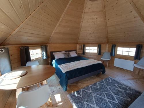 ein Schlafzimmer mit einem Bett und einem Tisch in einem Zimmer in der Unterkunft Les Cabanes du Grand Nord in Pradines