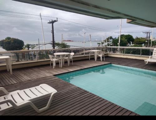 uma piscina com cadeiras e mesas num deque em Lindo Flat Beira Mar 401 em Fortaleza