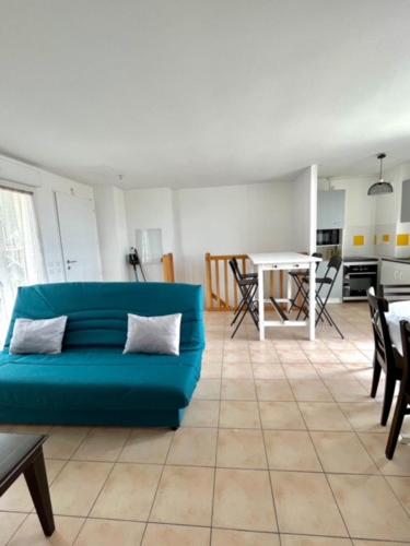 un soggiorno con divano blu e tavolo di Appartement front de l'océan a Soulac-sur-Mer