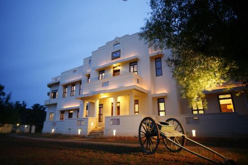 un grand bâtiment blanc avec un canon devant. dans l'établissement Visalam Chettinad Palace - CGH Earth, à Chettinadu