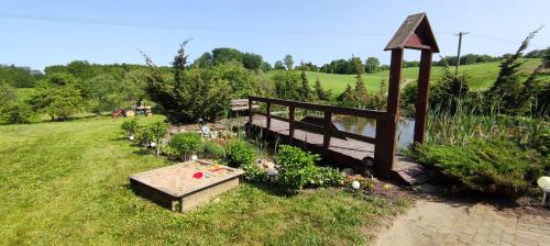 a wooden bench sitting in the grass next to a pond at Agroturystyka Radziucie in Radziucie