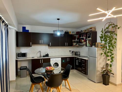 a kitchen with black cabinets and a table with chairs at Fat Cow Apartment 103 in Larnaka