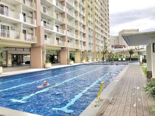 a person swimming in a swimming pool next to a building at Promo! BNew accessible 1BR condo w/ city view in Manila
