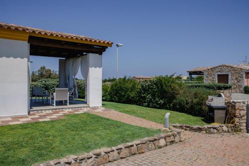 un jardín con patio y una casa en Le Residenze di Baia Sant'Anna en Tanaunella