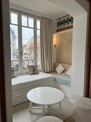 a living room with a couch and a table and a window at Villa La Rafale plage centre 300 m in Le Touquet-Paris-Plage