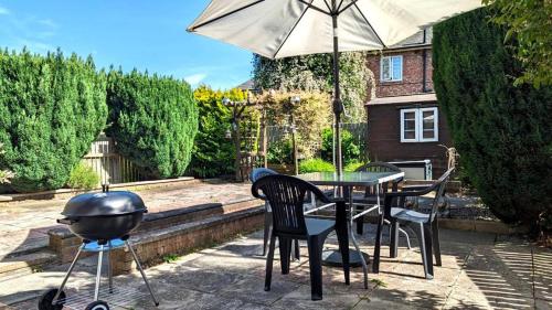 a grill and chairs and a table with an umbrella at Spacious home near Newcastle City Centre in Hebburn-on-Tyne