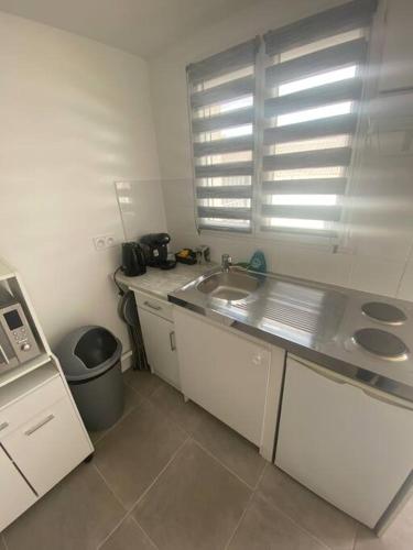 une petite cuisine avec un évier et une fenêtre dans l'établissement Très bel Appartement T2 près aéroport et Paris, à Claye-Souilly