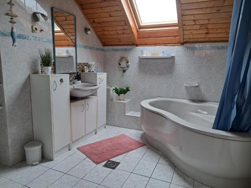 a bathroom with a large tub and a sink at Kismarosi Center Apartman in Kismaros