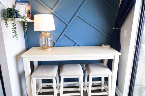 a table with two stools and a lamp on it at SeaRenity by the Sea - Luxury & Romance Await in Myrtle Beach
