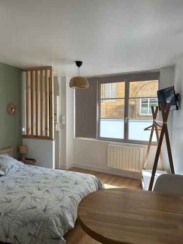 une chambre avec un lit, une table et une fenêtre dans l'établissement Les voiles, à Dieppe