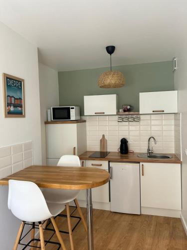 une cuisine avec une table en bois et des armoires blanches dans l'établissement Les voiles, à Dieppe