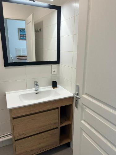 une salle de bain avec un lavabo et un miroir dans l'établissement Les voiles, à Dieppe