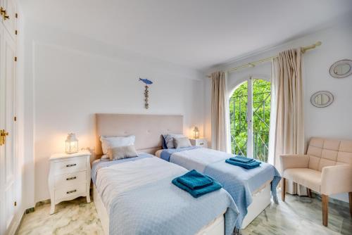 - une chambre avec deux lits, une chaise et une fenêtre dans l'établissement Estepona Beach Apartment, à Estepona