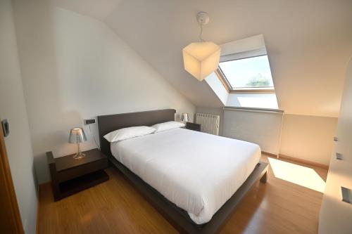 a bedroom with a white bed and a window at BICOS ao MAR in Rianjo
