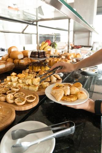 a person holding a plate of food in a buffet at Raf Hotel in Umuarama