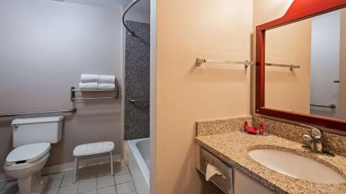a bathroom with a sink and a toilet and a mirror at SureStay Plus Hotel by Best Western Auburn in Auburn