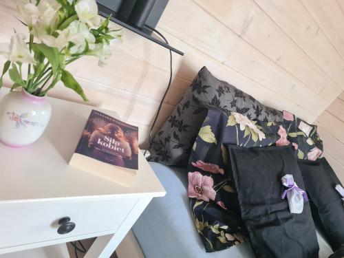 a couch with two pillows and a vase of flowers at Cuda Wianki in Zdów