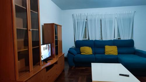 un sofá azul con almohadas amarillas en la sala de estar. en Gran piso en Ribadeo, en Ribadeo