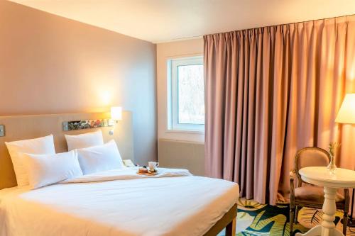 ein Hotelzimmer mit einem Bett, einem Tisch und einem Fenster in der Unterkunft Demeures de Campagne Parc du Coudray - Barbizon in Le Coudray-Montceaux