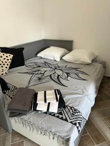 a bed with a black and white blanket and pillows at Charmant Studio dans villa - jardin privatif . in La Seyne-sur-Mer