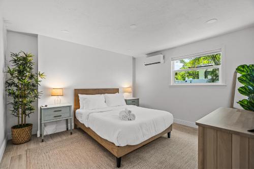 a white bedroom with a bed and a window at Enchanted Palms Villa in Boynton Beach
