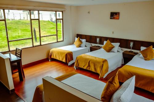 a room with two beds and a couch at Hotel Villa Vianney in Paipa