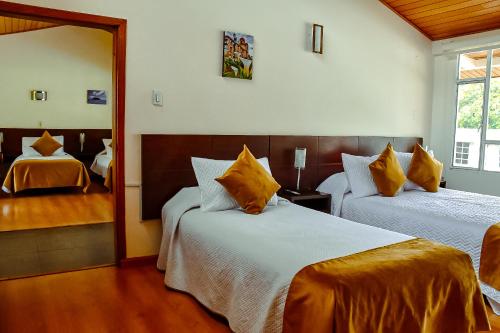 a hotel room with two beds and a mirror at Hotel Villa Vianney in Paipa