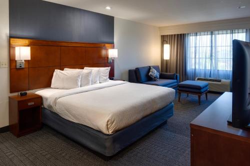 a hotel room with a bed and a television at Courtyard by Marriott Oklahoma City North/Quail Springs in The Village