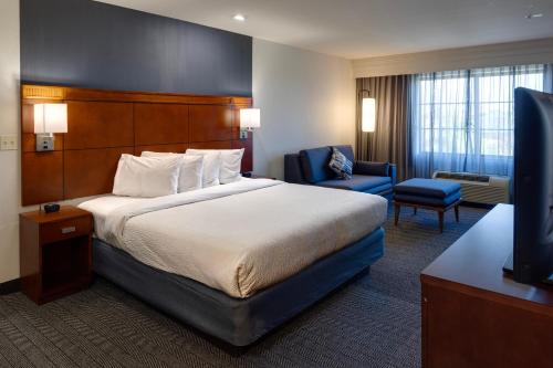 a hotel room with a bed and a television at Courtyard by Marriott Oklahoma City North/Quail Springs in Oklahoma City