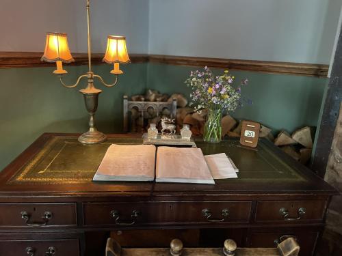 a desk with a book and a vase of flowers on it at White Hart Hotel in Wiveliscombe