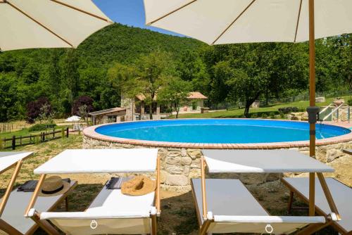 a swimming pool with two chairs and an umbrella at Lo Smarrino agriturismo in Gubbio