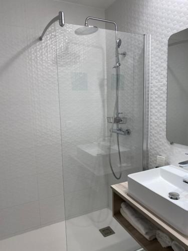 a white bathroom with a shower and a sink at Hôtel Saint-Clair, côté Plage in La Grande Motte