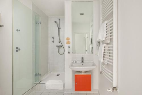a white bathroom with a sink and a shower at Mamaison Residence Sulekova Bratislava in Bratislava