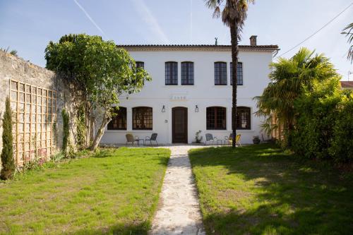 an exterior view of a white house with a palm tree at Maison et table d'hôtes Le Camélia Blanc in Saint-Ciers-sur-Gironde