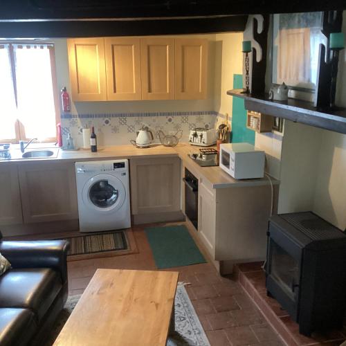 a kitchen with a washer and a sink and a table at La Petite Fleur in Javron-Les-Chapelles