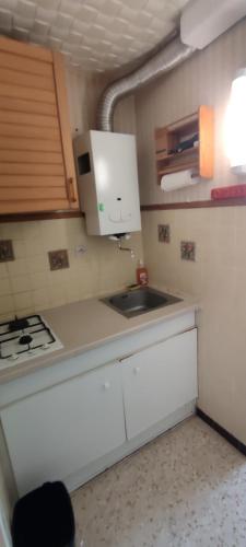 une petite cuisine avec un évier et une cuisinière dans l'établissement Studio et parking privé bord de mers, au Cap d'Agde